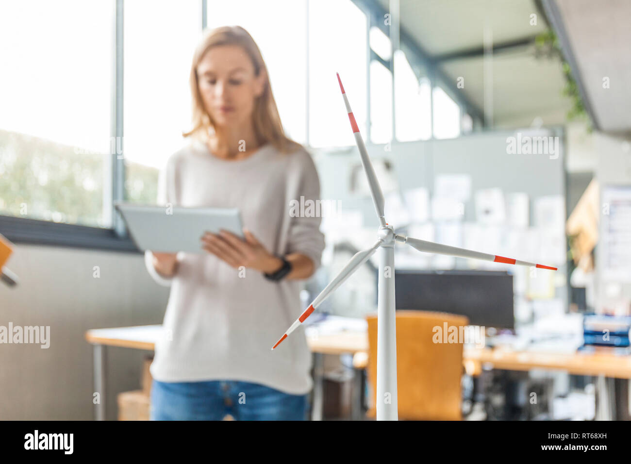 Woman in office avec modèle d'éolienne à l'aide de tablet Banque D'Images