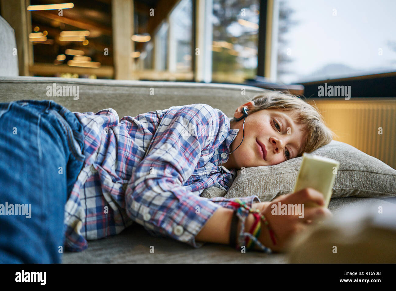 Garçon couché sur le canapé avec des écouteurs et un lecteur mp3 Banque D'Images