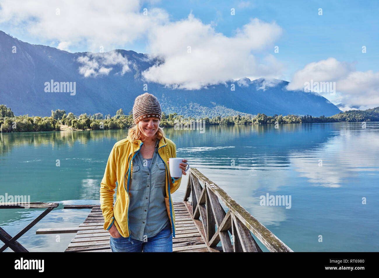 Chili, Lago Rosselot, Chaiten, woman walking on jetty holding mug Banque D'Images