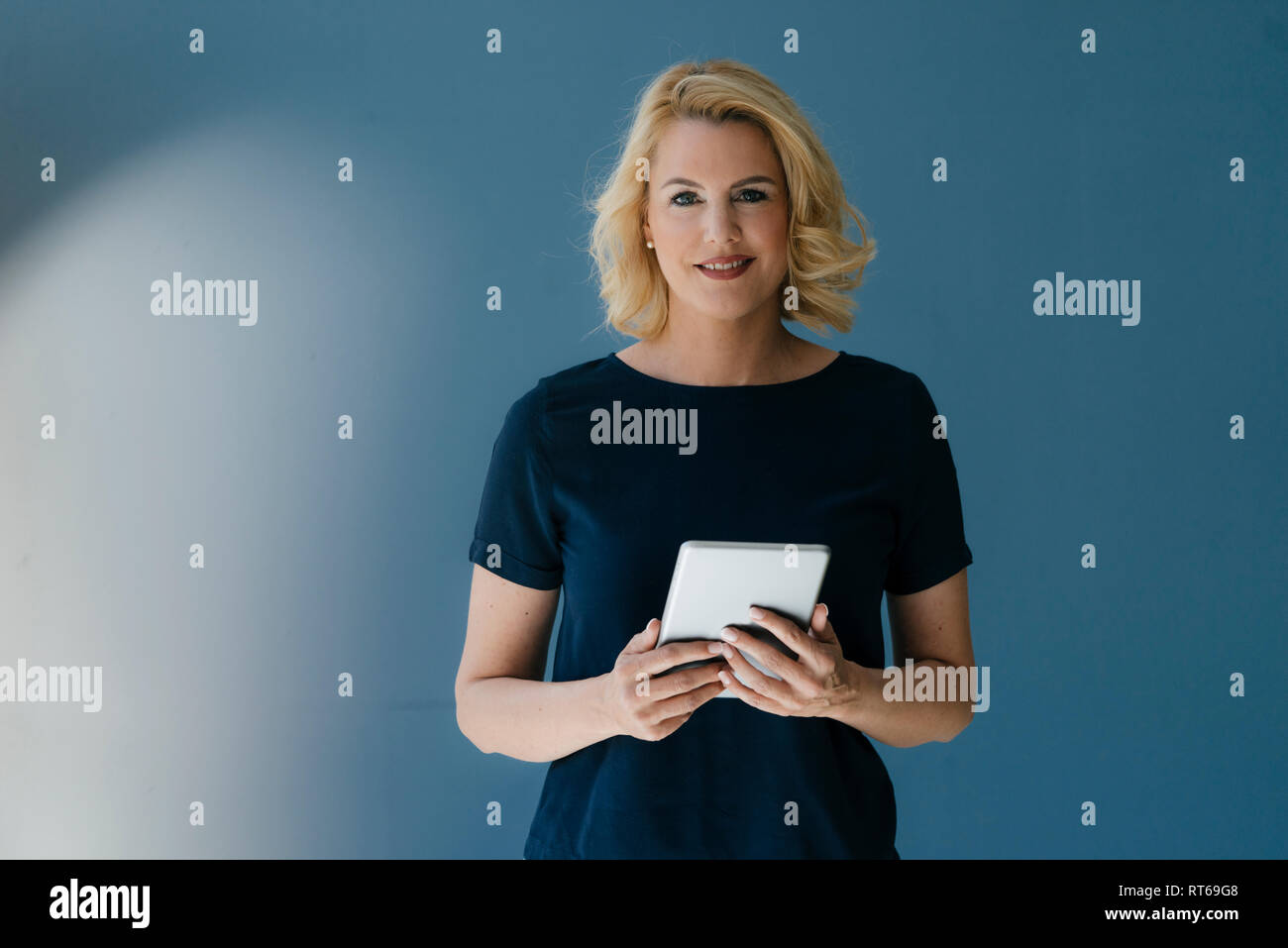 Portrait of smiling blond woman holding tablet Banque D'Images
