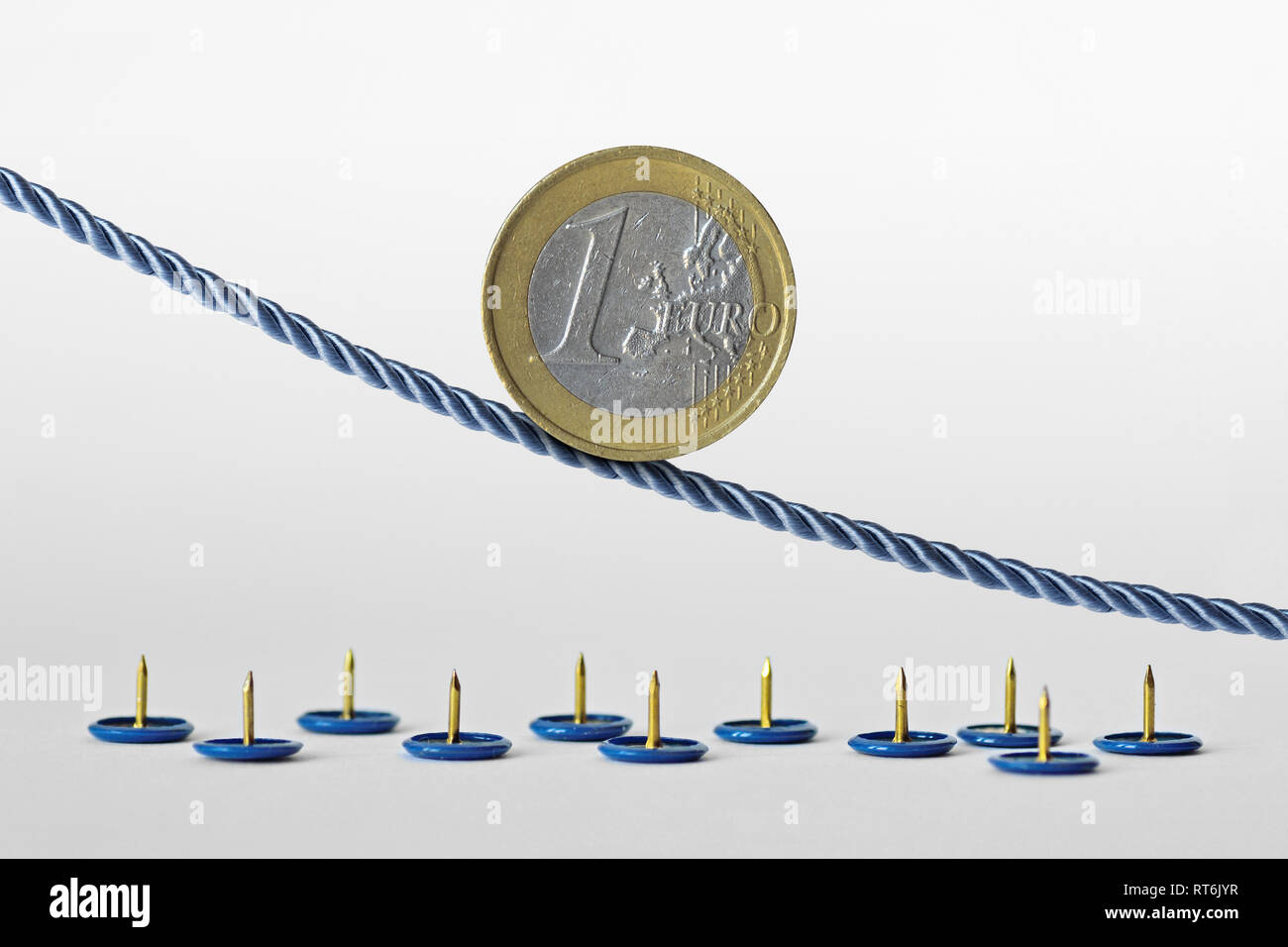 Pièce en euros sur corde sur des punaises - Concept de tendance à la baisse de l'euro et le risque de change euro Banque D'Images