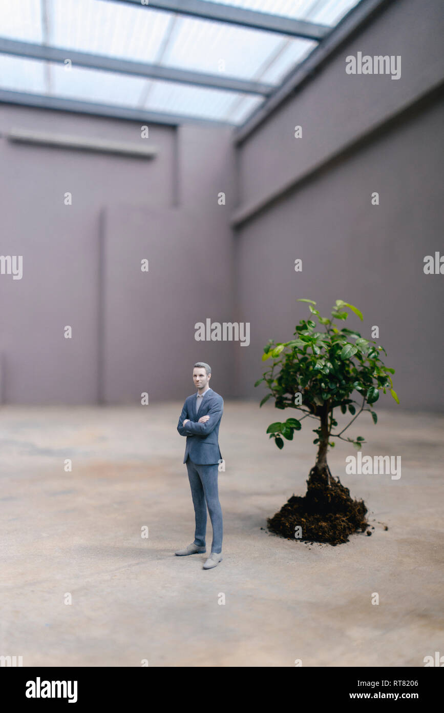 Figurine homme debout à côté d'un petit arbre Banque D'Images