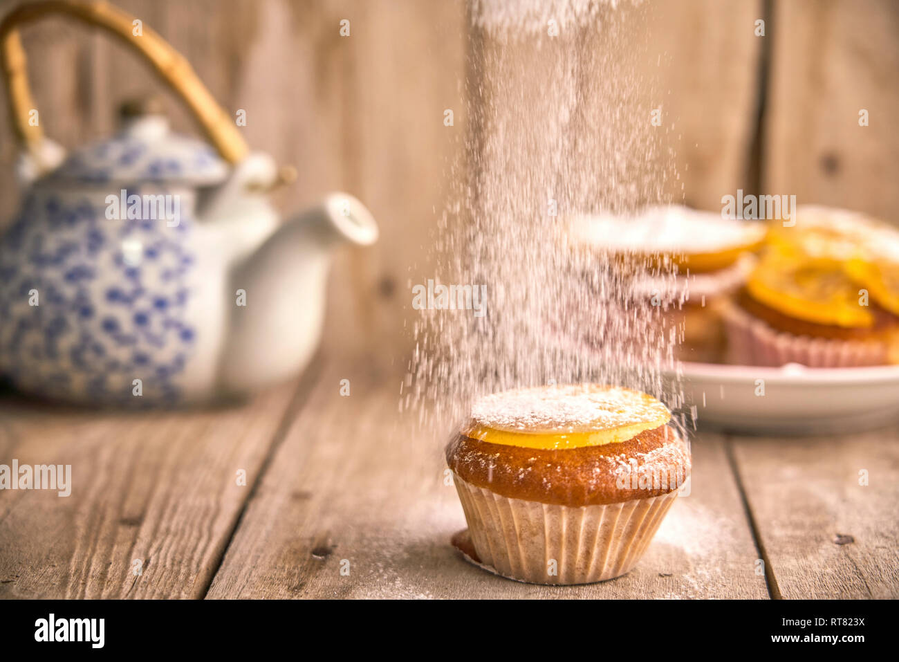 Saupoudrer de sucre à glacer sur muffin à l'orange confite sur le dessus Banque D'Images