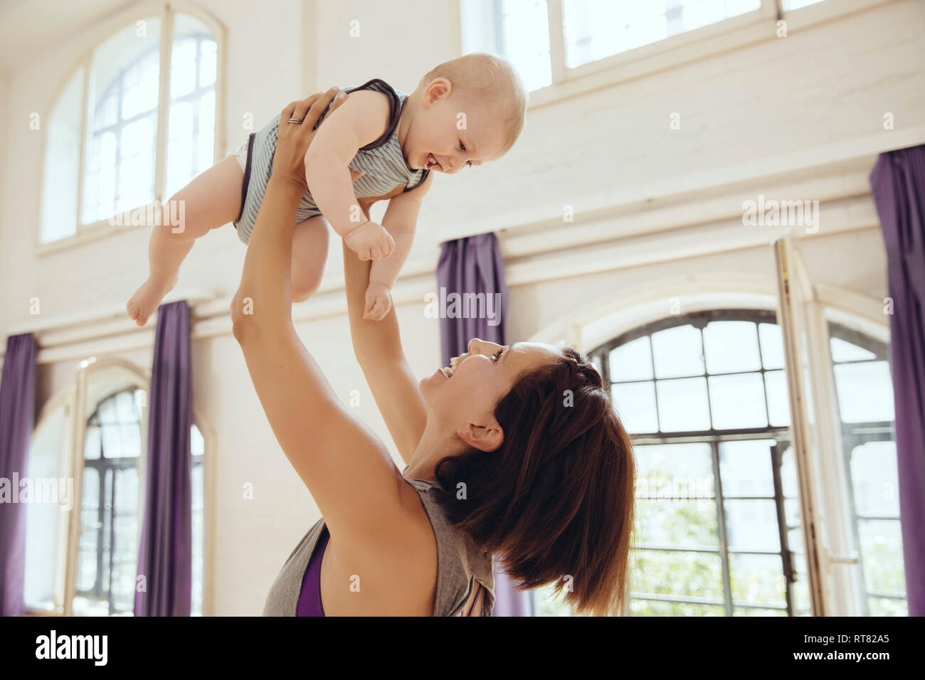 Sporty woman lifting up happy baby dans la salle de formation Banque D'Images