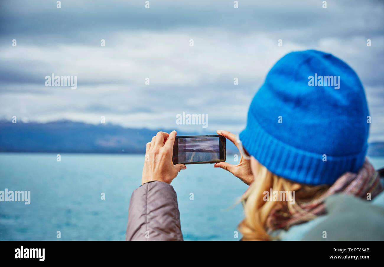 Le Chili, Puerto Rio Tranquilo, woman taking cell phone photo du lac et mountainscape Banque D'Images