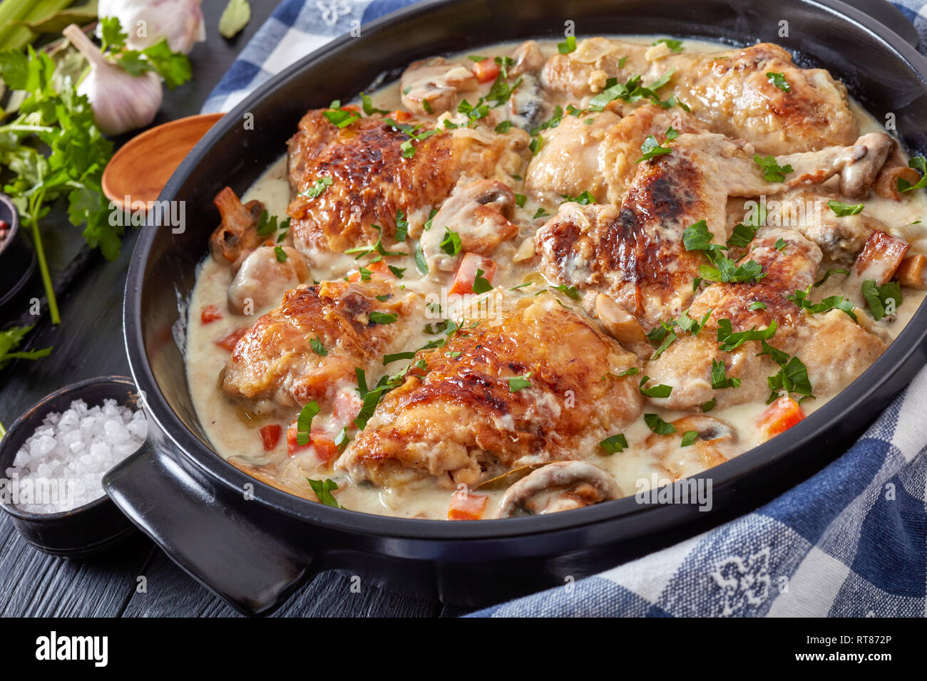 Close-up de la fricassée de poulet chaud dans une cocotte noire - la viande de poulet doré et mijotée dans du vin blanc, sauce crème aux champignons et légumes, cla Banque D'Images