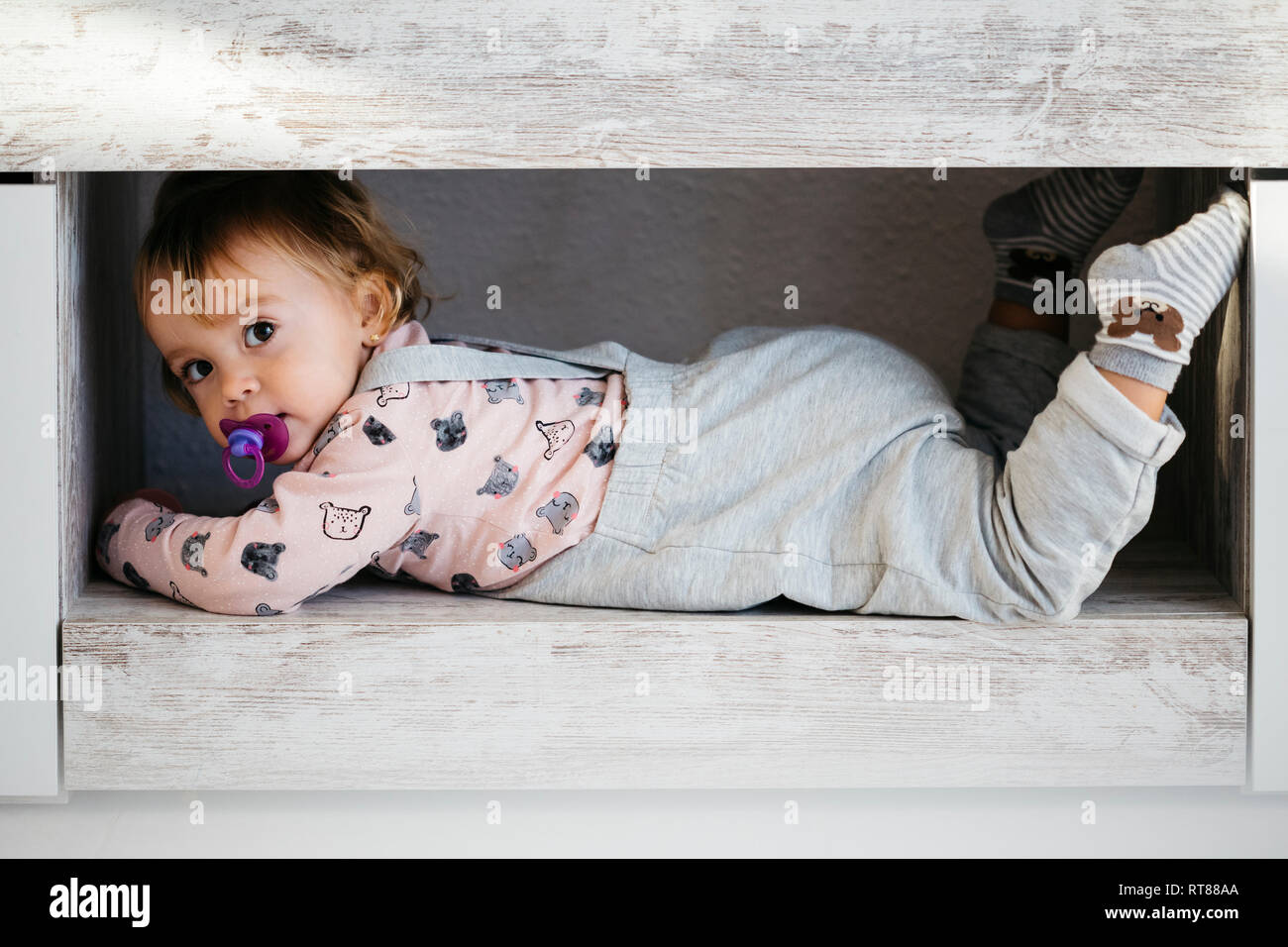 Portrait of baby girl avec sucette se cacher à la maison Banque D'Images