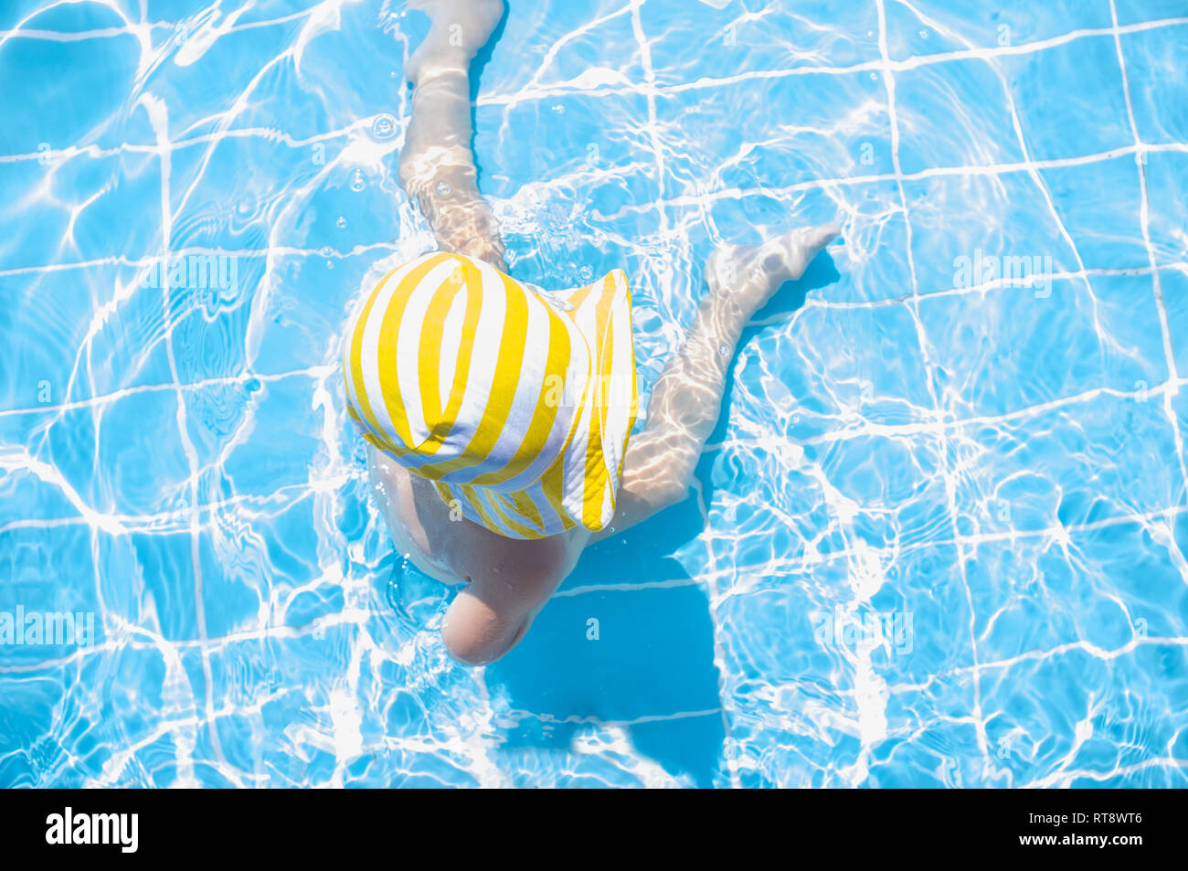 3 ans Bébé garçon profitant de la piscine de zone peu profonde. Il porte dénudée jaune hat Banque D'Images