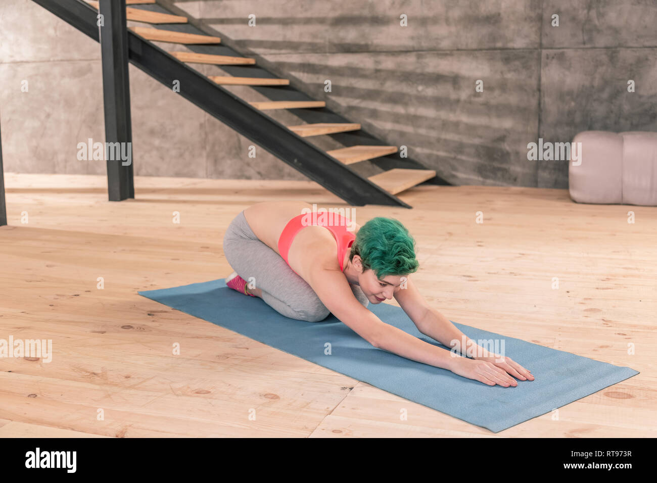 Femme aux cheveux verts qui s'étend à la lumière spacieux centre de remise en forme Banque D'Images