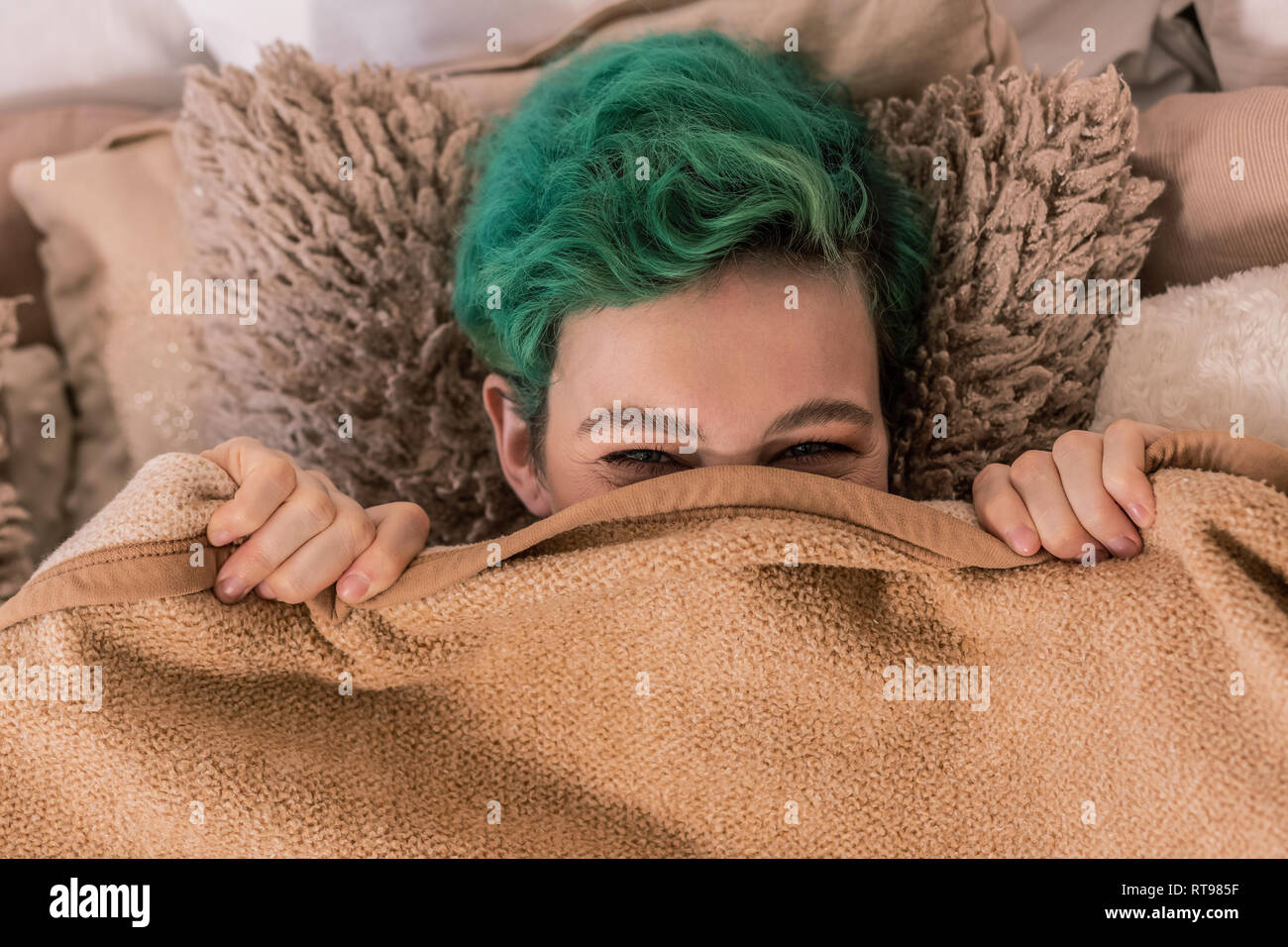 Green-haired woman lying on brown plaid moelleux oreiller sous Banque D'Images