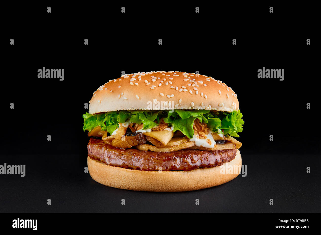 Hamburger parfait avec escalope de boeuf, champignons, laitue isolée au fond noir. Copy space Banque D'Images