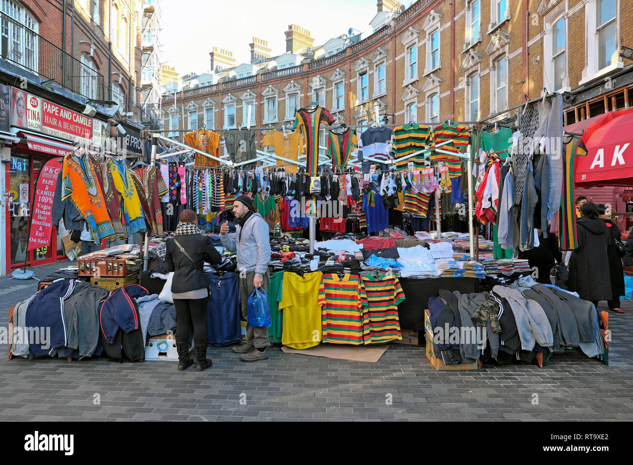 Un commerçant du marché de vente de vêtements pour hommes l'homme et maillots de football à Brixton street market Electric Avenue Brixton sud de Londres Angleterre Royaume-uni KATHY DEWITT Banque D'Images