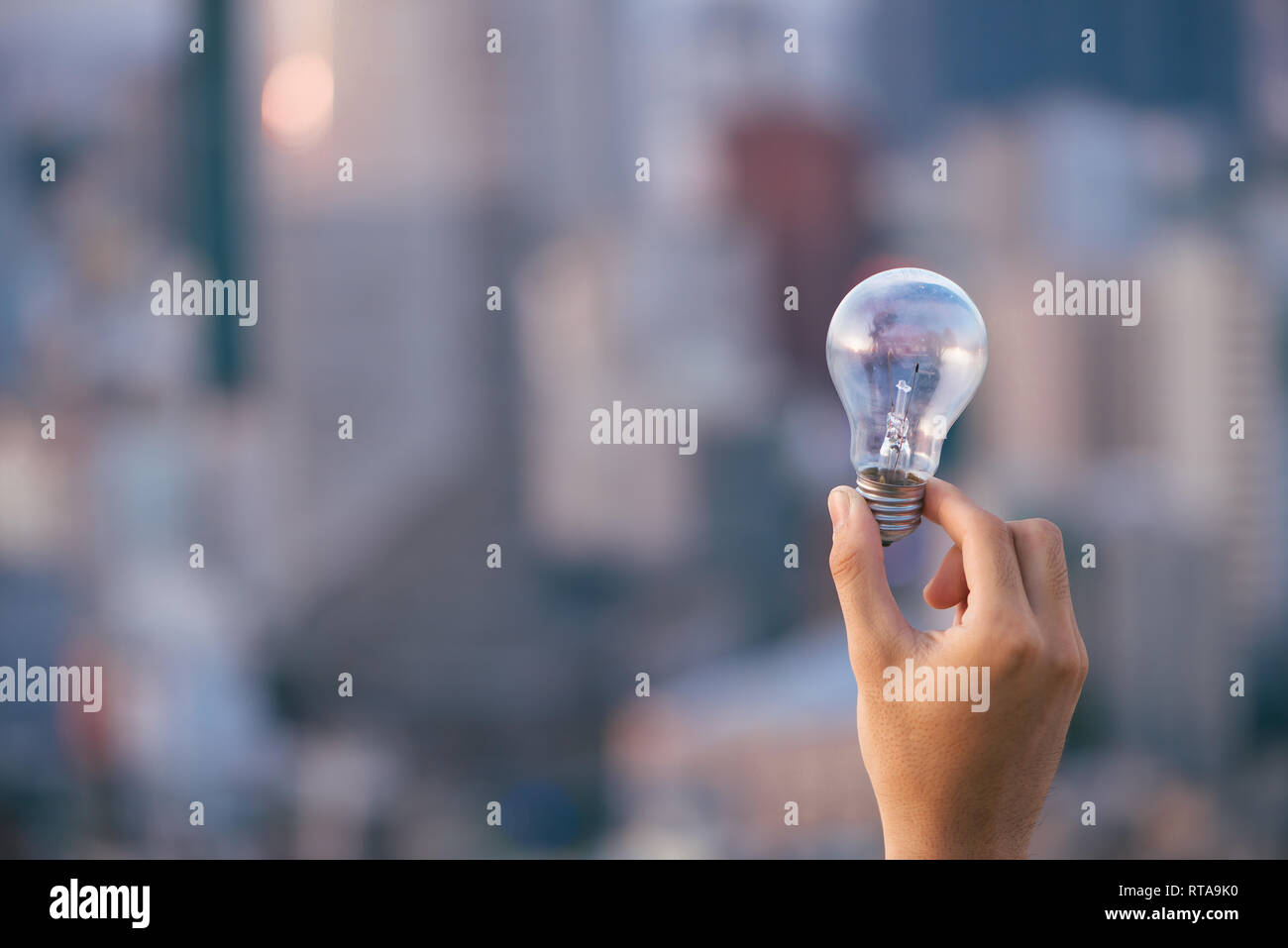 Coucher du soleil au-dessus de l'ampoule ampoule maisons urbaines. lampe transparent sur l'énergie solaire en milieu urbain, la cité, la ville de la vie nocturne. Symbole, concept de busi Banque D'Images
