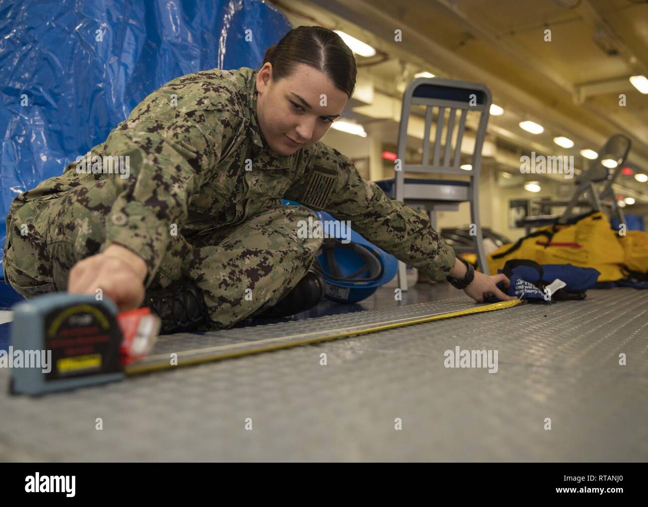 NEWPORT NEWS, Virginie (fév. 7, 2019) Carilann Marin Parr, de Harrisburg (Pennsylvanie), affectés à l'USS Gerald R. Ford (CVN 78) Service du pont, des mesures de l'eau un Firefly lumière Bug pour un conservateur de vie pendant l'entretien. Ford est actuellement en post shakedown la disponibilité de Huntington Ingalls Industries-Newport News Shipbuilding. Banque D'Images