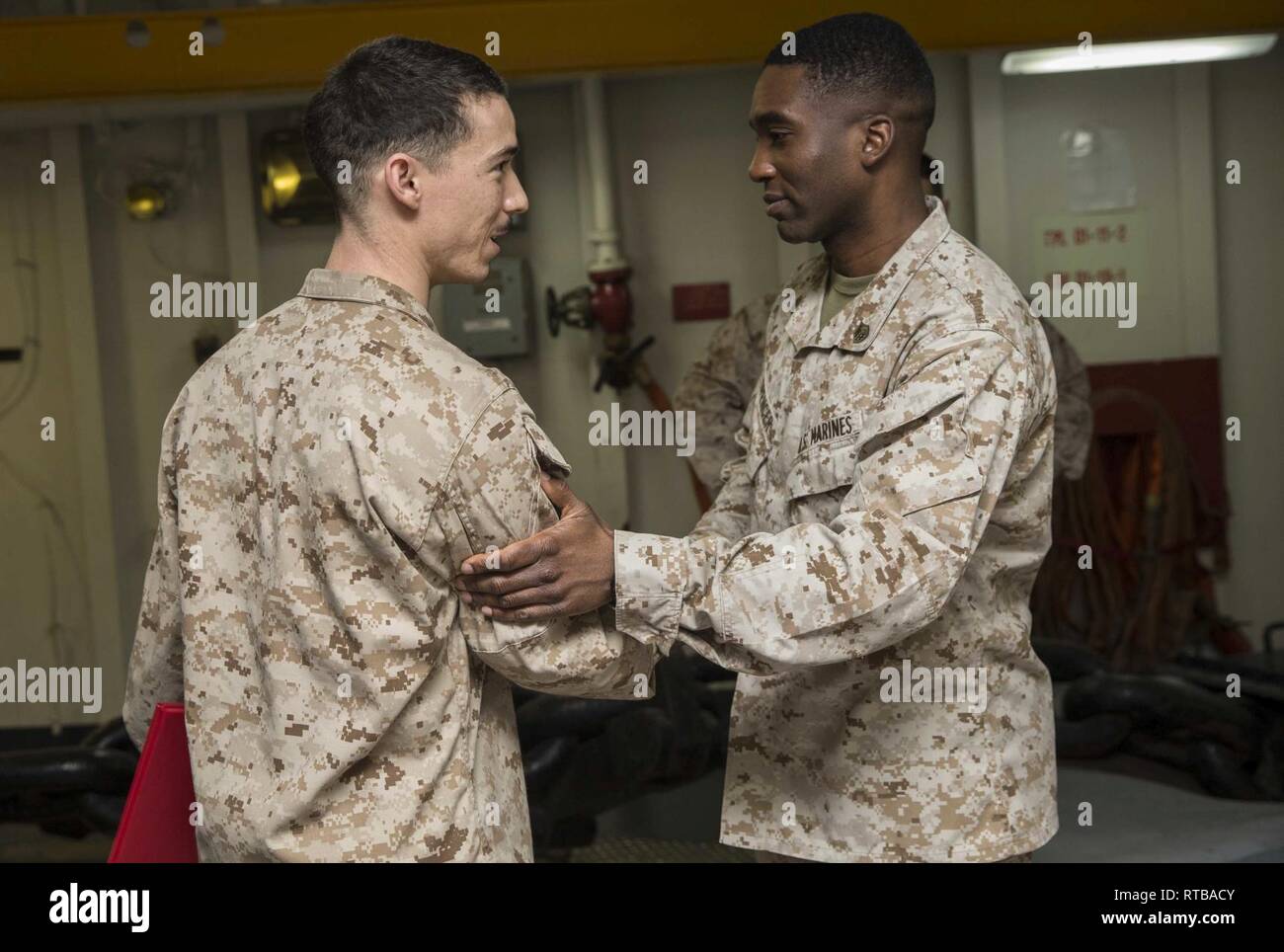 Le Sgt. Jamieson Clarke, à gauche, avec le chef juridique 22e Marine Expeditionary Unit reçoit les félicitations de sergent. James Spencer, le 22e MEU, chef d'entrepôt à la suite de sa promotion au grade de sergent dans le fo'c'sle, ou gaillard, de l'USS Kearsarge LHD (3), le 2 février 2019. Marines et de marins avec la 22e Marine Expeditionary Unit et groupe amphibie Kearsarge sont déployés dans le domaine de la 5e flotte américaine des opérations à l'appui des opérations navales pour assurer maritme la stabilité et la sécurité dans la région Centrale, reliant la Méditerranée et le Pacifique par la Western Indian Oc Banque D'Images