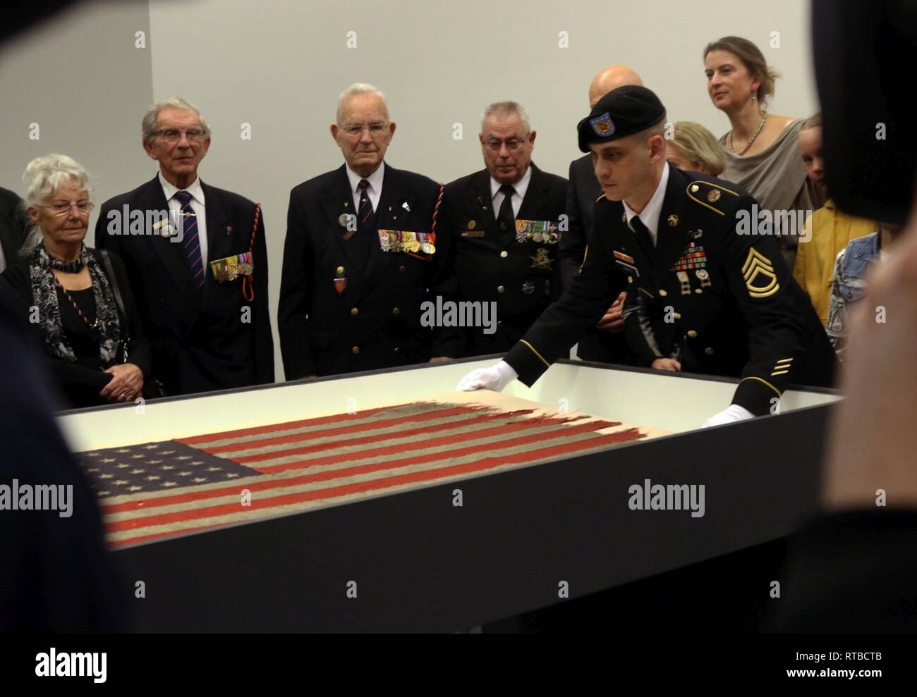 Le Sgt. 1re classe Christopher Jones avec le Siège de l'entreprise et de l'Administration centrale, de l'armée américaine établit la garnison Benelux D-Day flag dans une vitrine pendant une journée d'exposition, la cérémonie du drapeau 4 fév. au Musée Kunsthal de Rotterdam, Pays-Bas. Le D-Day d'un drapeau qui flottait sur un navire de la Marine américaine menant l'avance des alliés sur les plages de Normandie il y a près de 75 ans sera retourné à l'Amérique après être allé sur l'affichage dans les Pays-Bas le 5 février - mai 17. Banque D'Images