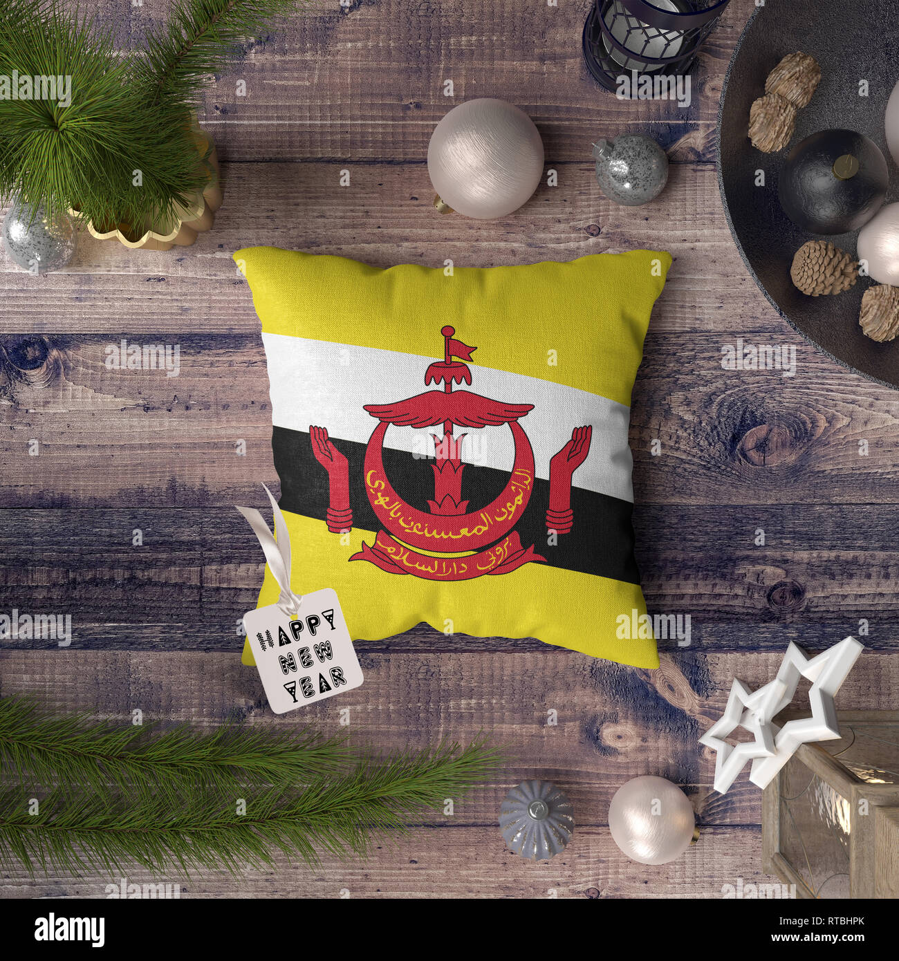 Bonne année tag avec drapeau Brunéi sur l'oreiller. Concept de décoration de Noël sur la table en bois avec belle objets. Banque D'Images