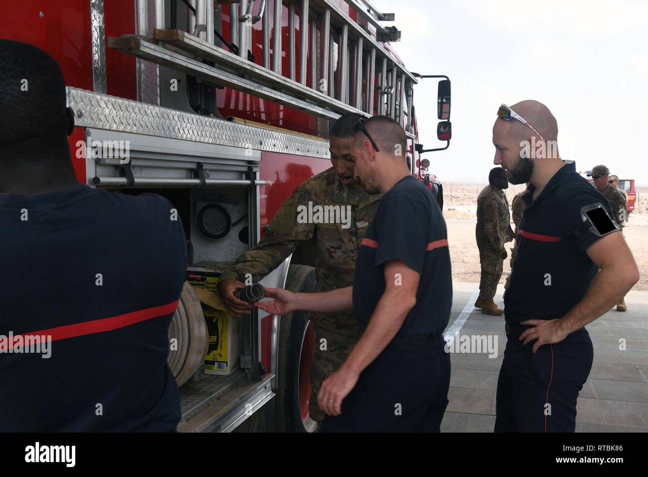 Les cadres supérieurs de l'US Air Force Airman Floyd Dawkins, 870e Escadron expéditionnaire de la fire department conducteur opérateur, discute avec des membres de l'Armée de l'air sur les spécifications du P-18 camion-citerne à eau à l'Aérodrome de Chebelley, Djibouti, le 8 février 2019. L'U.S Air Force a reçu le pétrolier de la Marine américaine, l'augmentation de leurs capacités de lutte contre les incendies structurels à. Banque D'Images