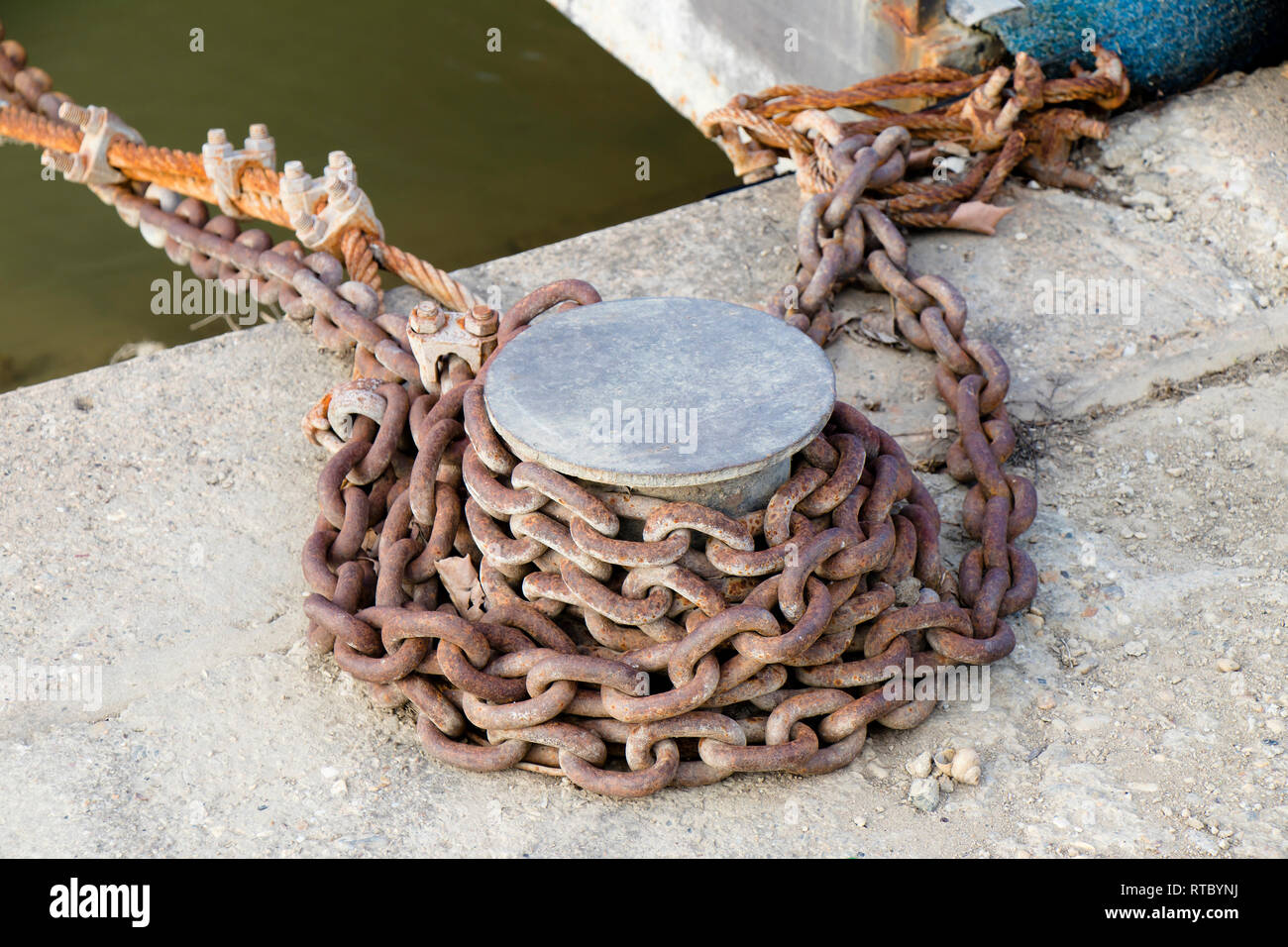 Borne d'amarrage avec chaîne rouillée sur la rivière à quai, Close up Banque D'Images