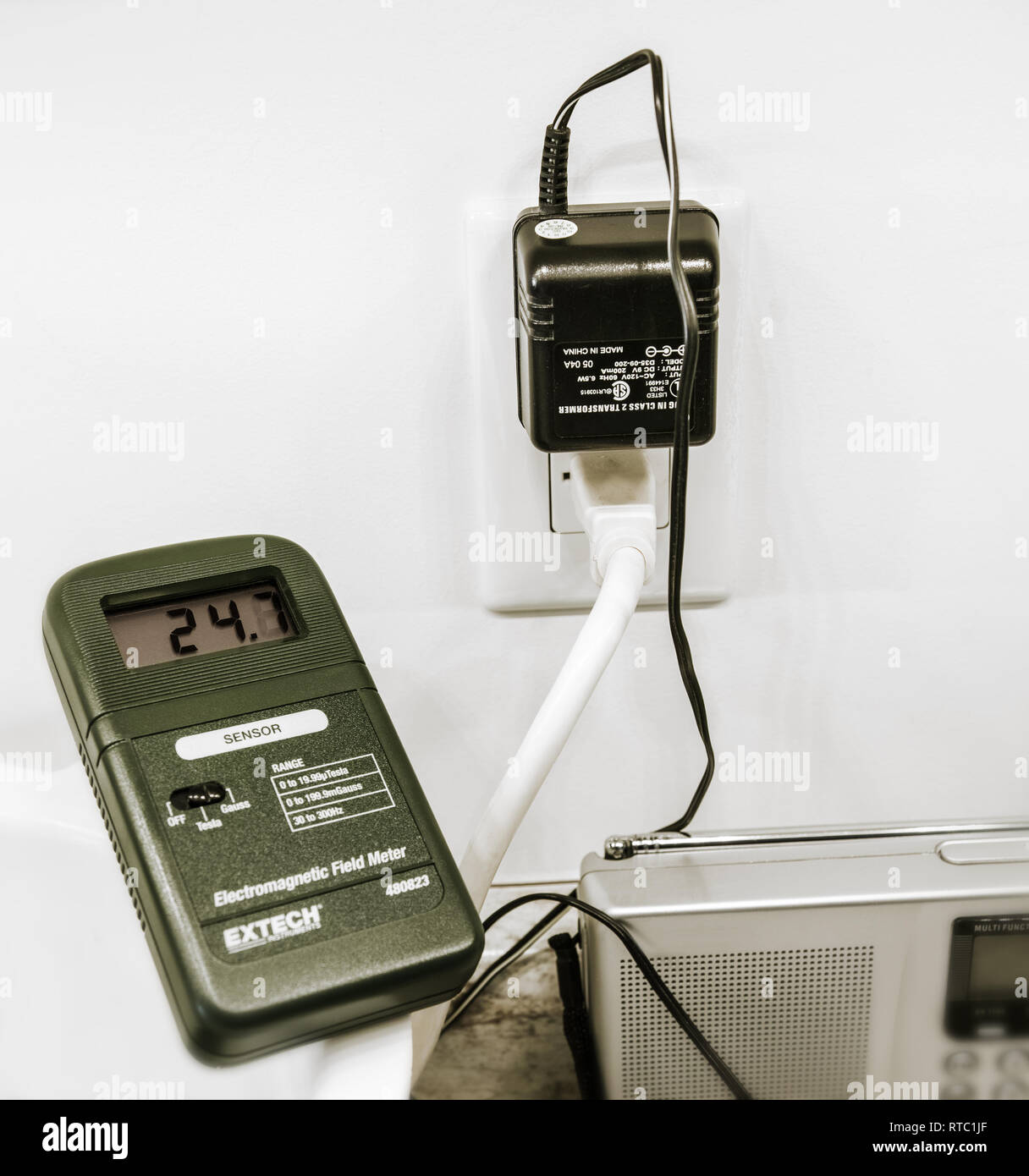 Le compteur de champ électromagnétique mesure de très grandes quantités d'émissions provenant d'un petit transformateur mural (unités Gauss). Distance approximative: 20 cm. Banque D'Images