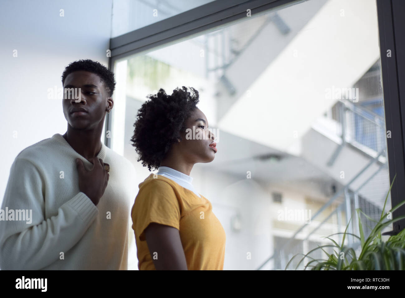 Un jeune couple noir attrayant à la recherche sérieuse dans une simple chambre blanche à la mode moderne, séance photo. Banque D'Images