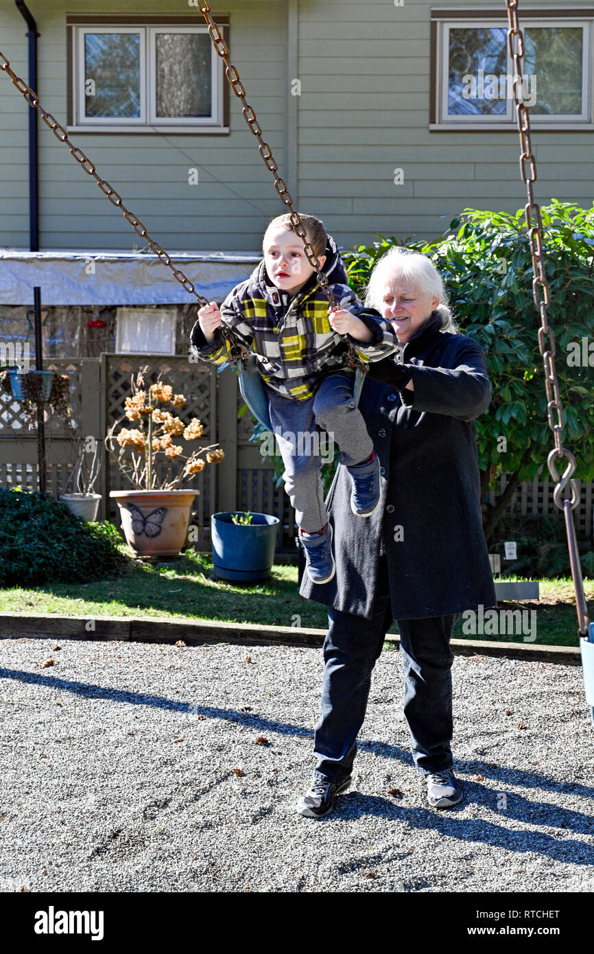 Grand-mère poussant sur l'aire de swingswing garçon Banque D'Images