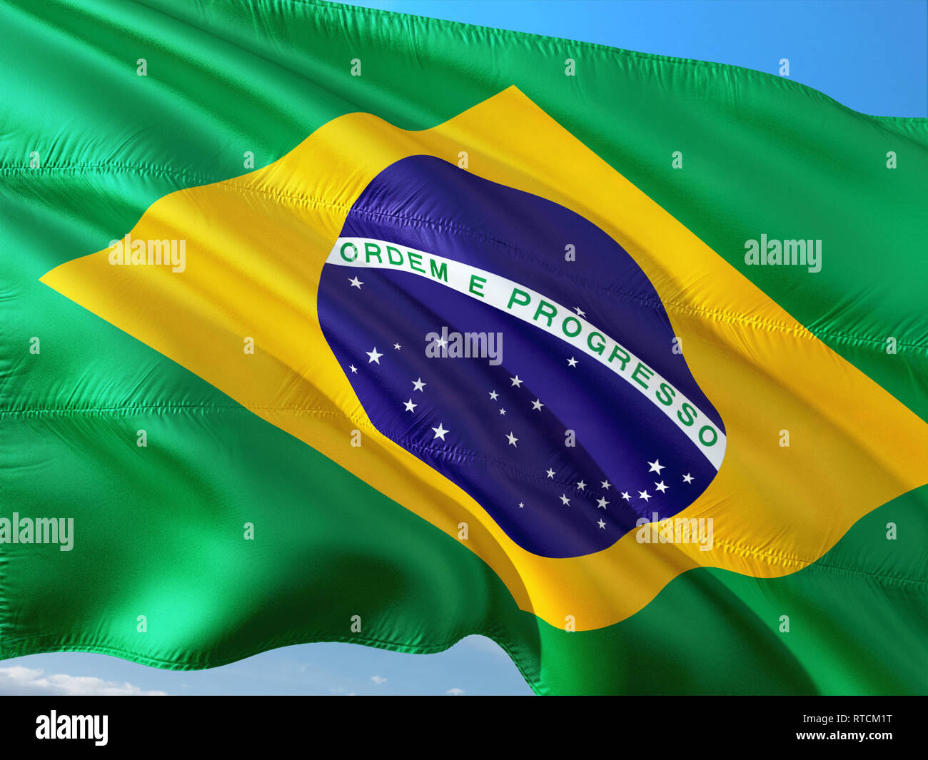 Drapeau du Brésil dans le vent contre ciel bleu profond. Tissu de haute qualité. Banque D'Images