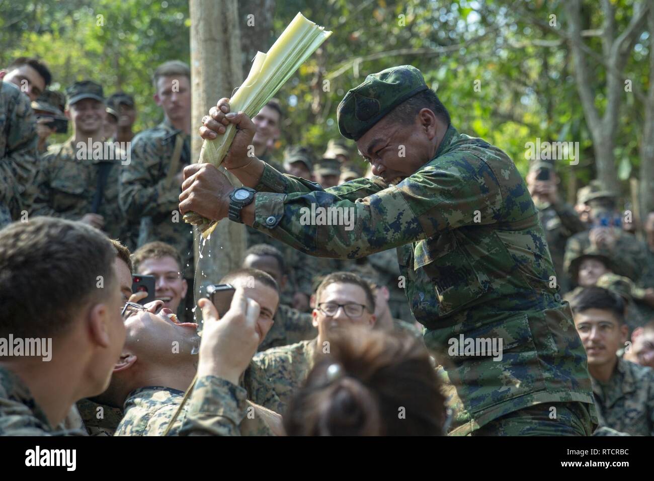 Une Marine royale thaïlandaise tire l'eau d'un bananier dans la bouche d'un bataillon de marines avec l'équipe d'atterrissage, 1er Bataillon, 4ème Marines, au cours de la formation à la survie dans la jungle, l'exercice Gold Cobra 19, camp de Ban Chan Khrem, Khao Khitchakut District, Thaïlande, le 15 février 2019. Gold Cobra exercice démontre l'engagement du Royaume de Thaïlande et des États-Unis à notre alliance de longue date, fait la promotion des partenariats régionaux et les progrès de la coopération en matière de sécurité dans la région Indo-Pacifique. La 31e unité expéditionnaire de marines, le Corps des Marines' seulement continuellement de l'avant-déployés MEU, fournit une flexibl Banque D'Images