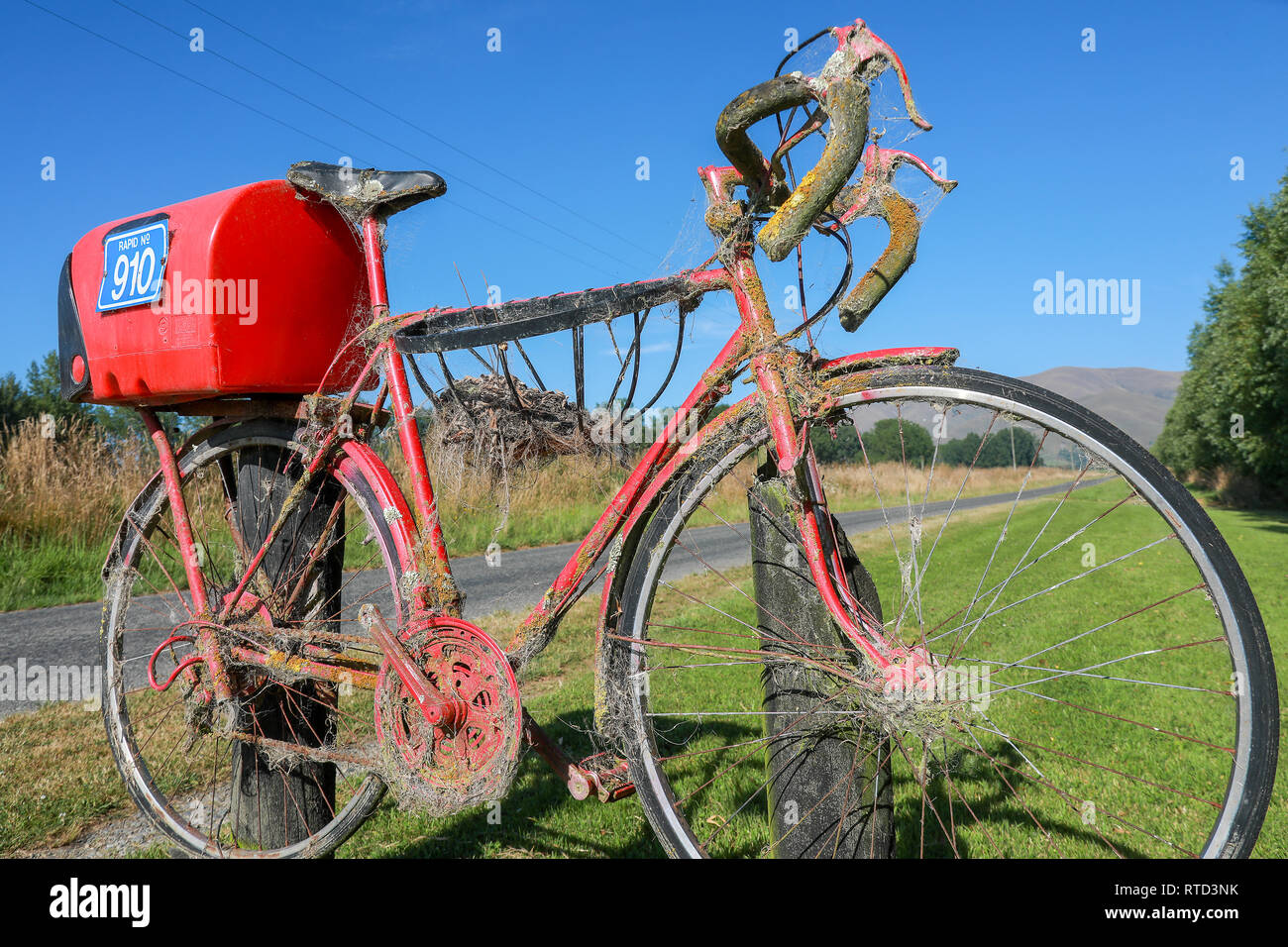 Une boîte aux lettres boîte aux lettres rouge attaché à une course vélo de route sur une route de campagne en milieu rural de l'île du sud de Nouvelle-Zélande Banque D'Images