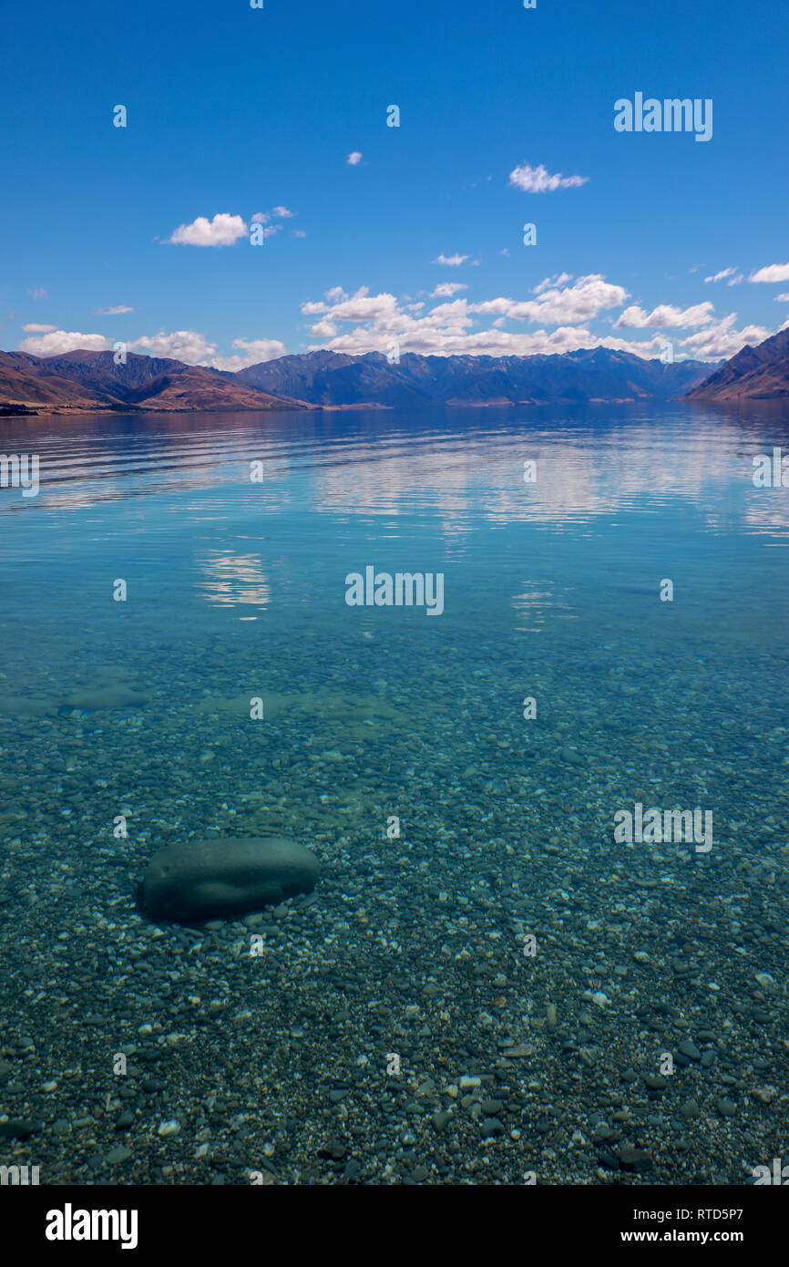 Magnifique Lac Hawea en été, ciel bleu de l'eau claire les roches cailloux nuages Nouvelle-zélande Île du Sud Banque D'Images