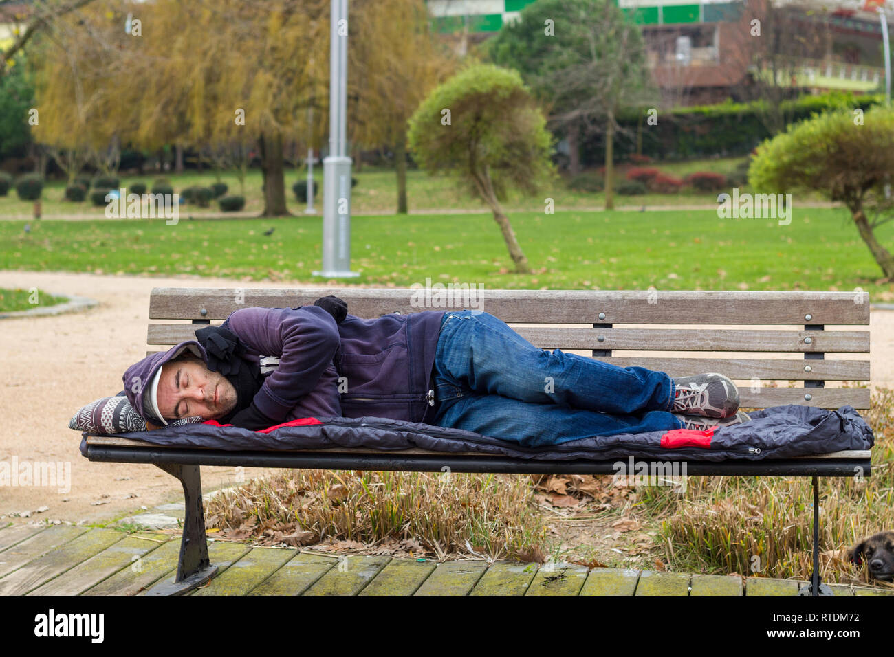 Sans-abri dormant sur un banc du park Banque D'Images