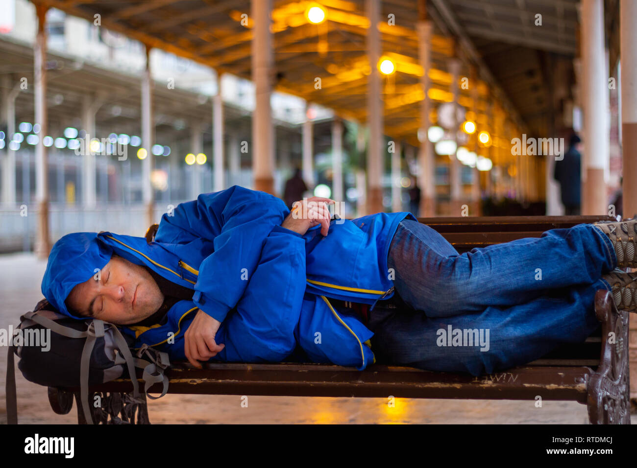 Banc passager man sleeping on at train station Banque D'Images