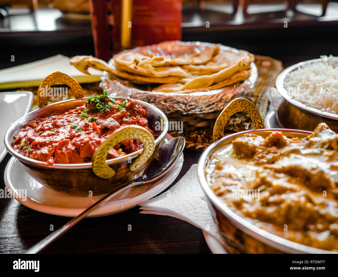 La nourriture indienne ou indien Curry dans un cuivre laiton servant bol oriental, des morceaux de filet de poulet au curry ingrédients de la sauce dans une casserole avec l'ancienne table Banque D'Images