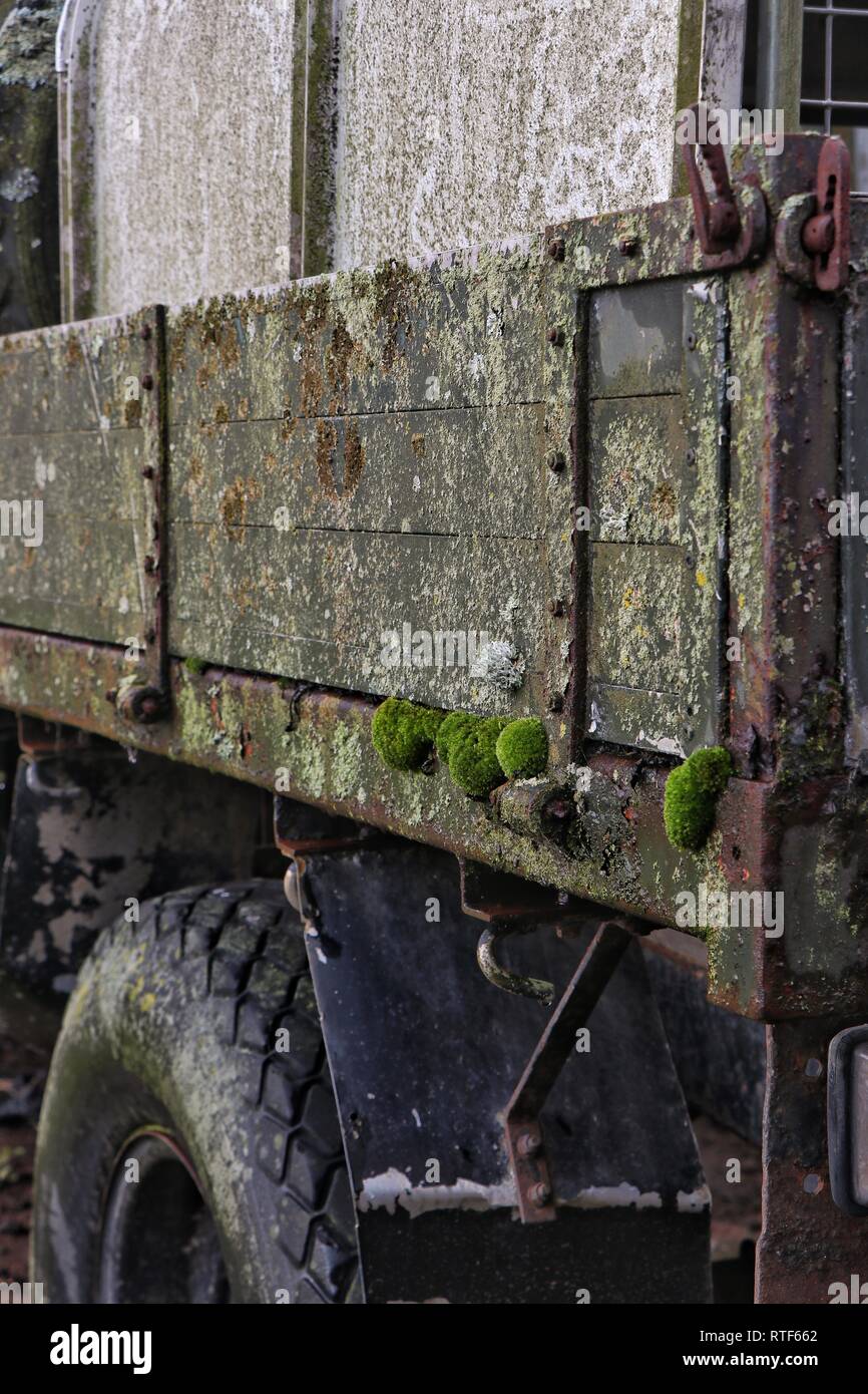 Moss pousse sur un vieux agricultural land rover avec côtés en bois, comme il se décompose lentement dans un champ d'agriculteurs. Banque D'Images