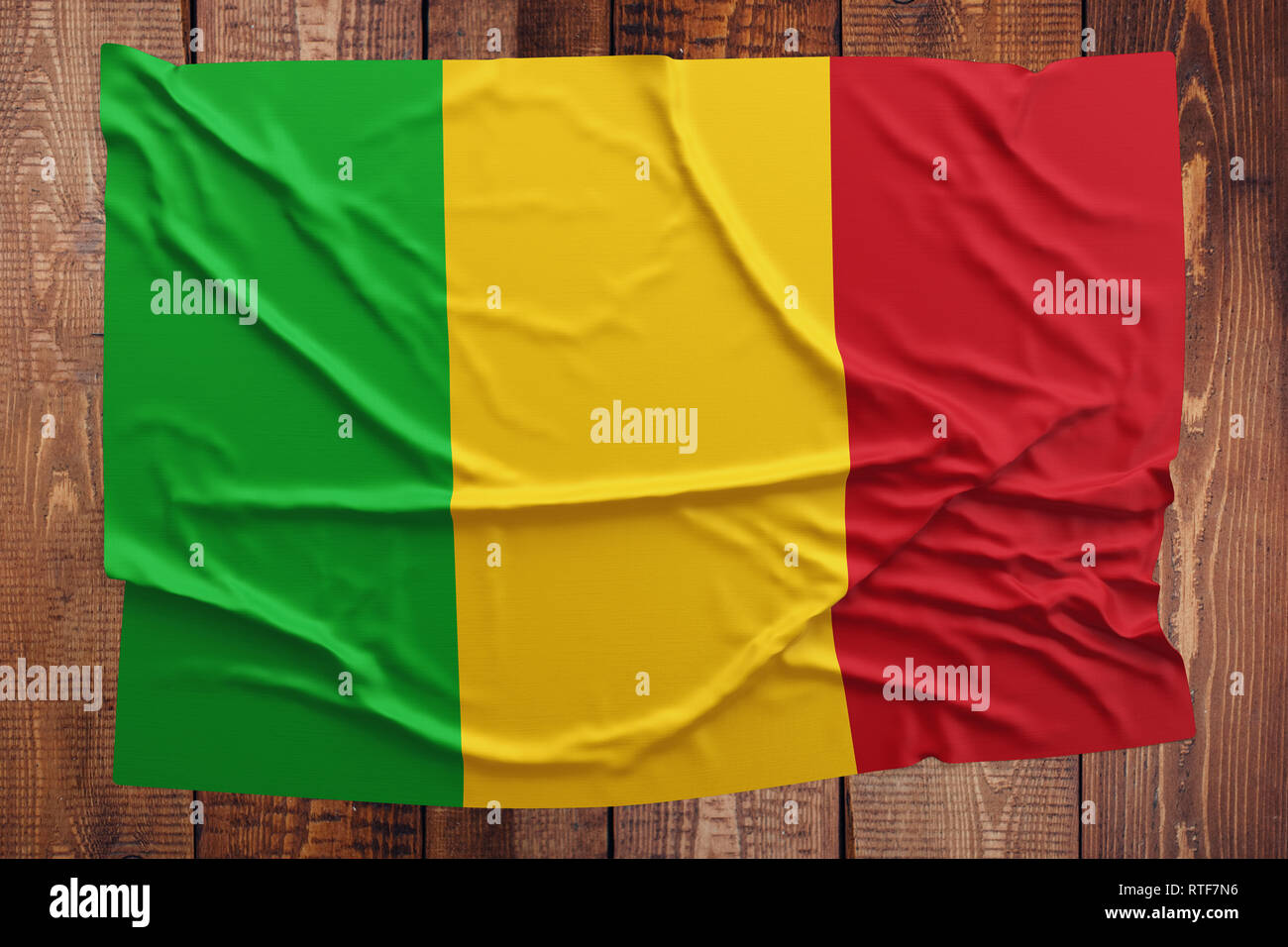 Pavillon du Mali sur une table en bois. Drapeau malien froissé vue d'en haut. Banque D'Images