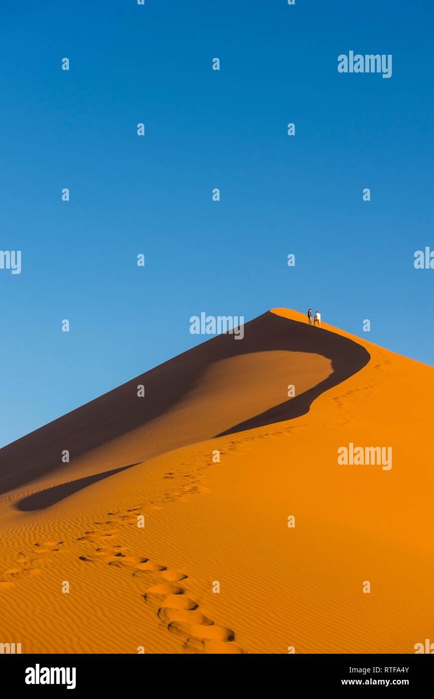 Femme marche vers le haut de la Dune 45 sanddune géant, Namib-Naukluft National Park, Namibie Banque D'Images