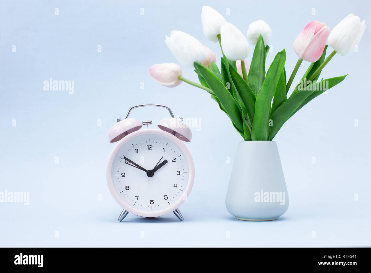 Réveil rose et un bouquet de fleurs sur fond bleu le Printemps ! Banque D'Images