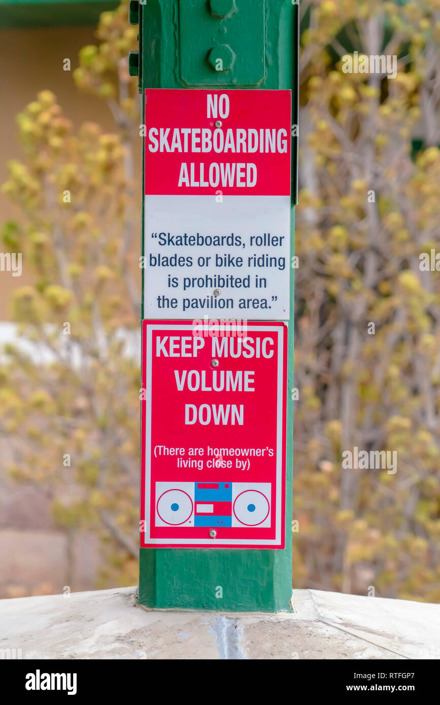 Close up of les panneaux de réglementation sur un pavillon public. Close up de panneaux de signalisation en bois vert vissé à un post sur un pavillon. Les signes lire pas Skateb Banque D'Images