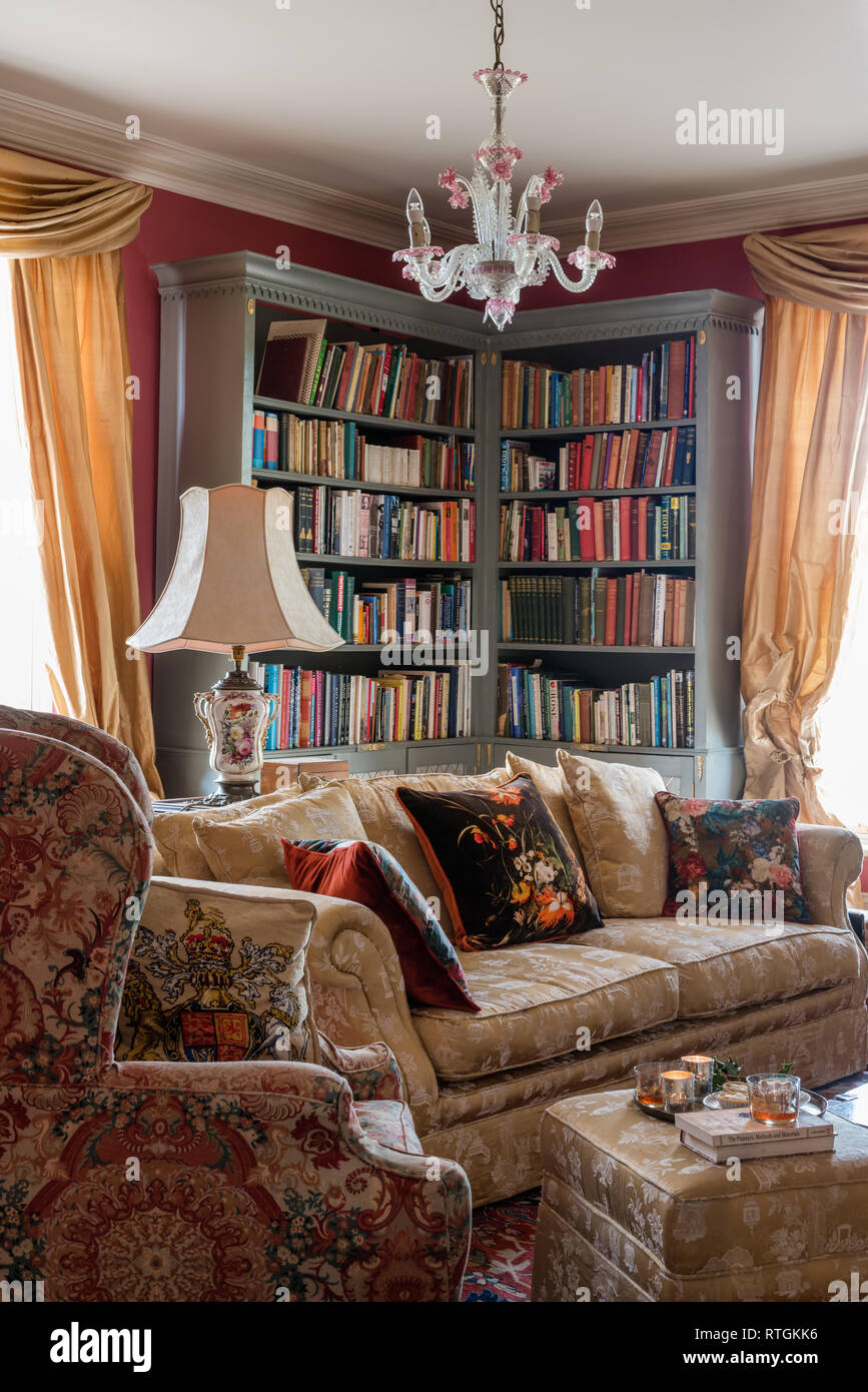Bibliothèque d'angle avec des rideaux à fleurs d'or et de canapé et fauteuil Banque D'Images