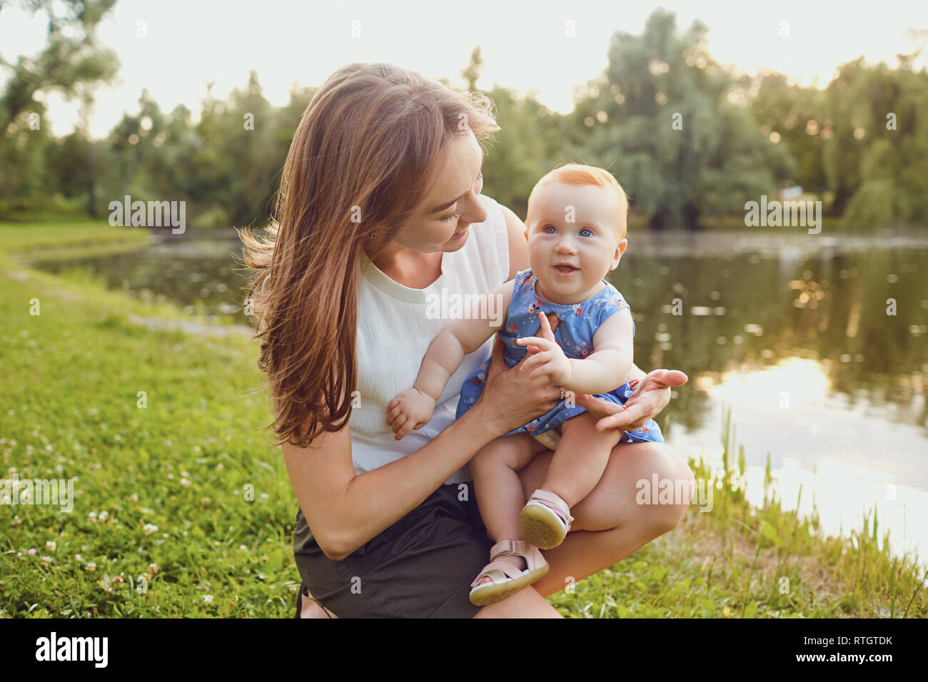 La mère et l'enfant jouant sur l'herbe en parc. Banque D'Images