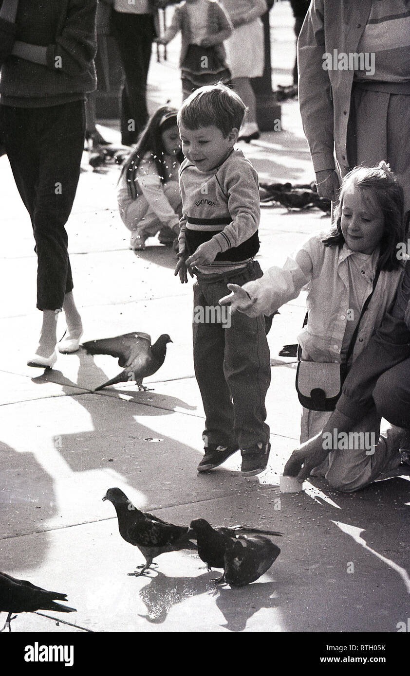 Années 1970, Trafalgar Square, Londres, excité les jeunes enfants nourrir les pigeons. Ces oiseaux sauvages utilisées pour flock à la place au grand amusement pour les nombreux visiteurs, avant que les nouveaux règlements mis en place en 2001 a les nourrir une infraction. Banque D'Images