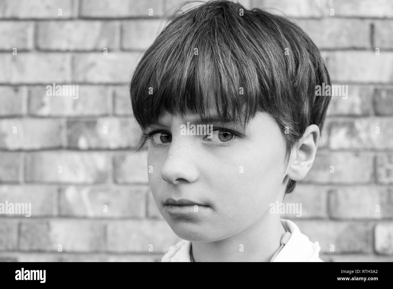 Portrait noir et blanc d'un enfant aux cheveux courts avec de grands yeux et un regard en colère Banque D'Images