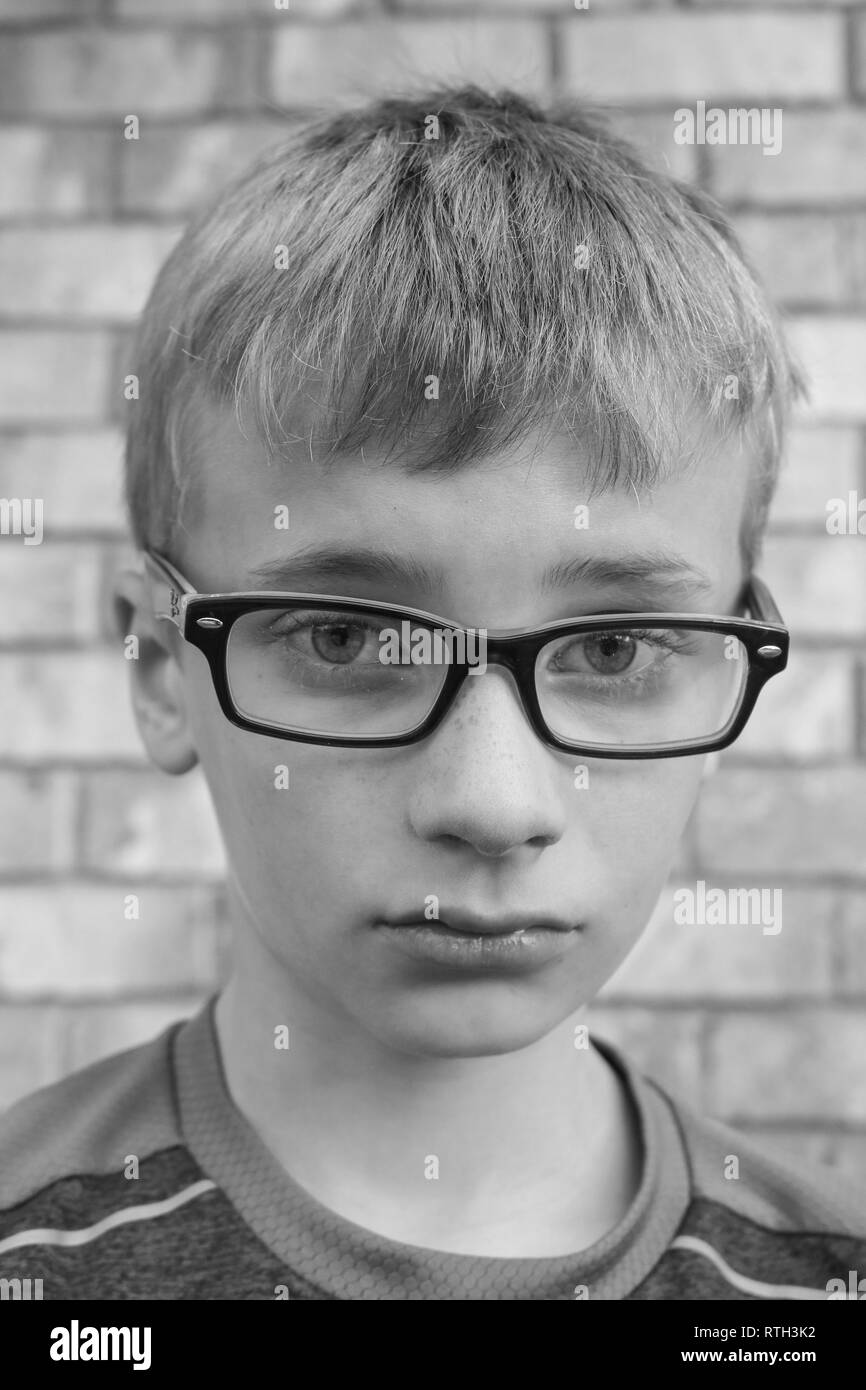 Portrait noir et blanc d'un triste contrarié boy wearing black lunettes Banque D'Images