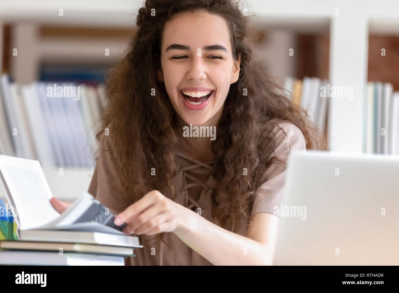 Teen girl laughing étudiant pendant ses études avec des livres et d'ordinateurs portables Banque D'Images