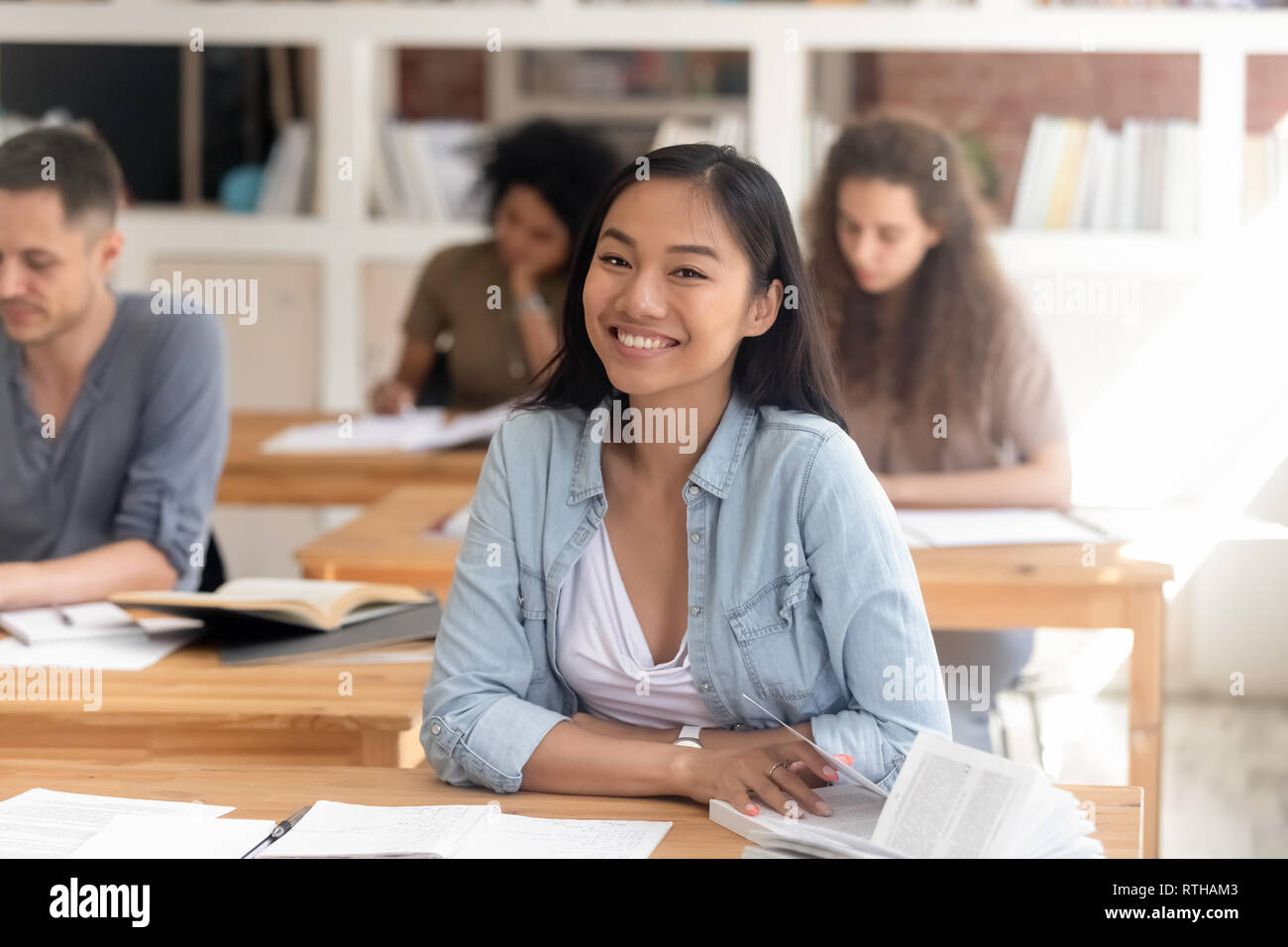 Smiling smart asian student looking at camera sitting at desk Banque D'Images