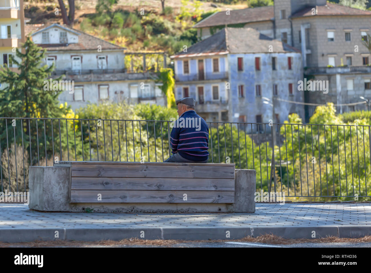 Viseu / Portugal - 1005 2018 : senior woman relaxing assis sur un banc en bois et béton sur le bord d'un trottoir pour piétons road Banque D'Images