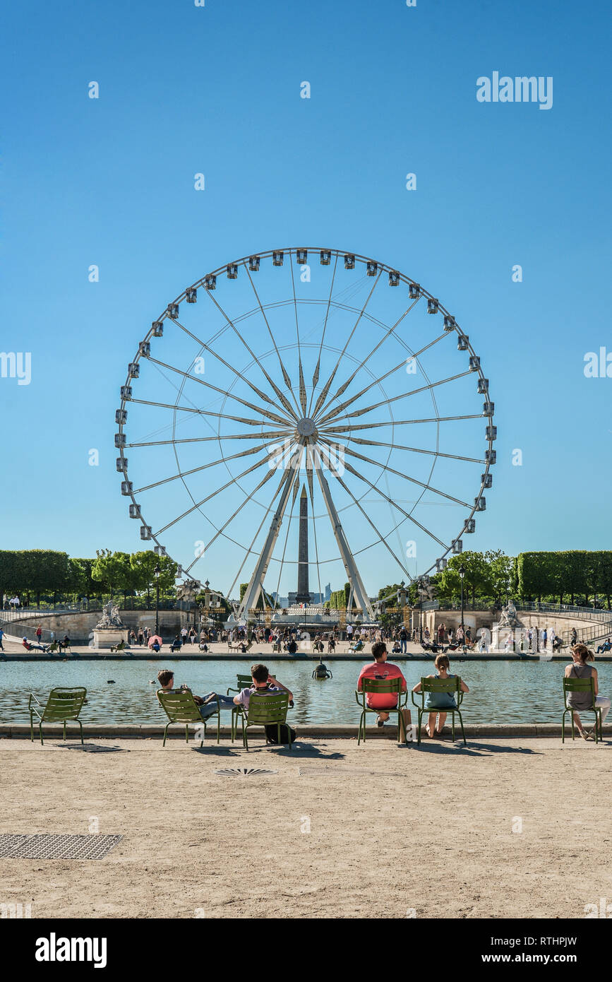 Paris, France - le 7 mai 2018 : des gens assis et se reposer près de l'étang dans le jardin des Tuileries en face de la grande roue à Paris en journée ensoleillée Banque D'Images
