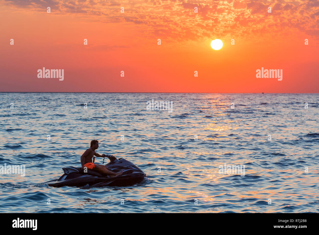 Man riding jet ski sur soleil colorés sur la mer Banque D'Images