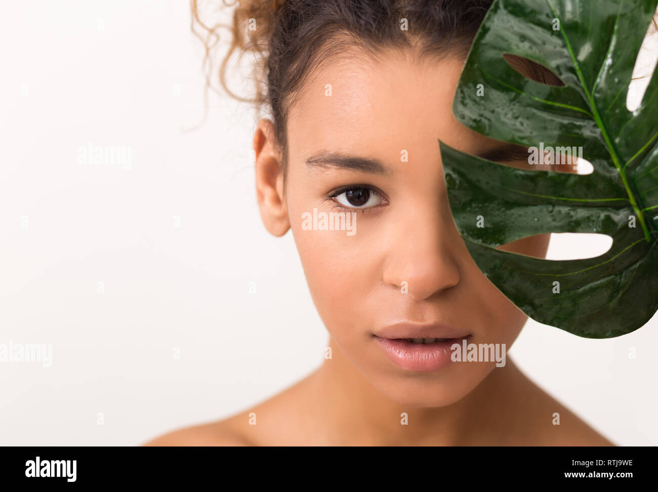 African-american woman with tropical vert feuille, fond clair Banque D'Images