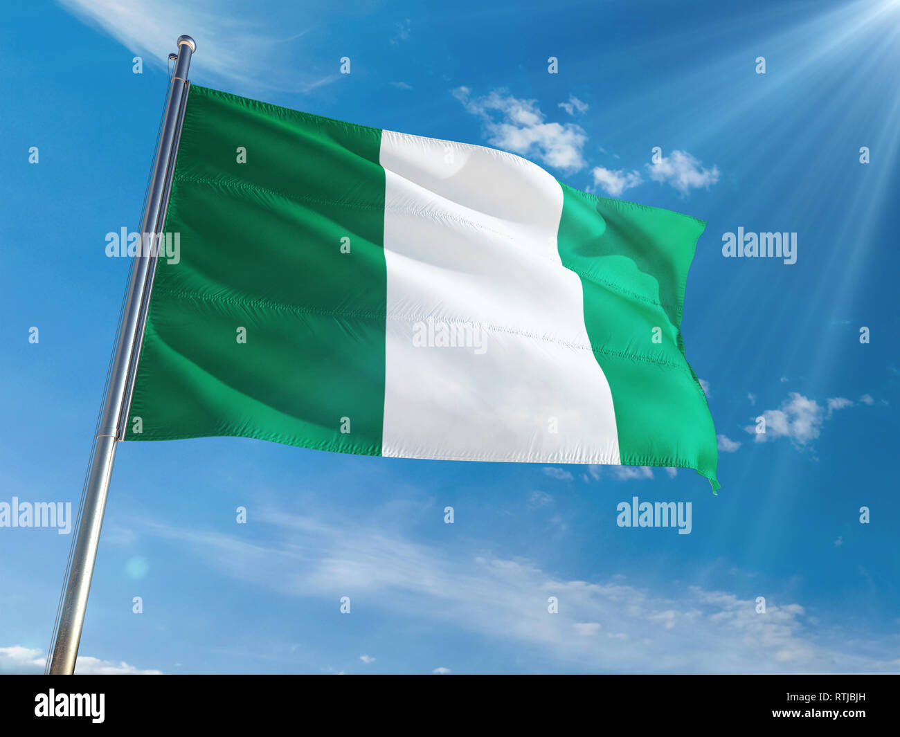 Le Nigeria de brandir le drapeau national sur le poteau contre sunny blue sky background. La Haute Définition Banque D'Images